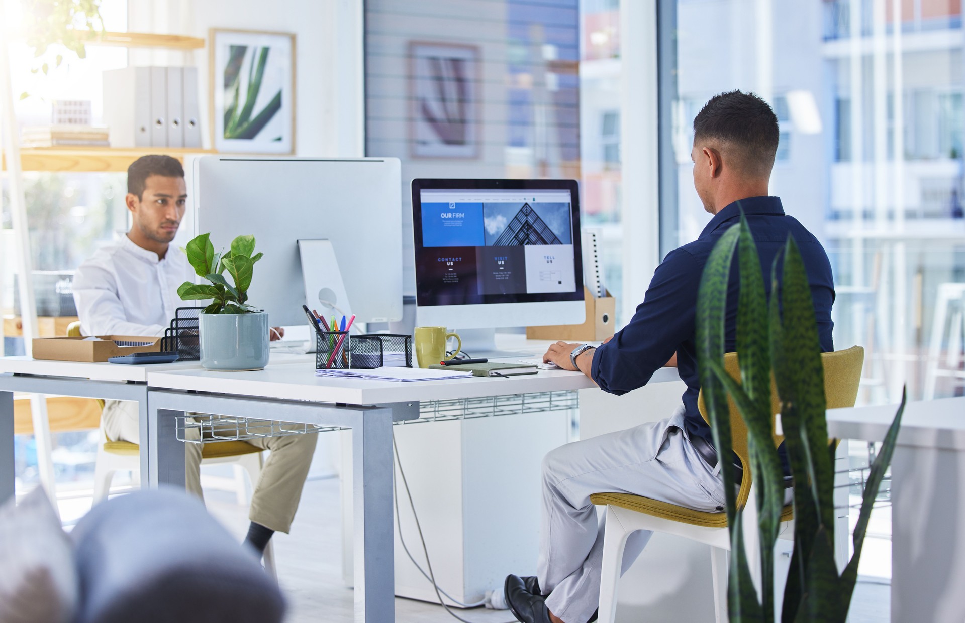 Shot of two men working on their computers in a modern office