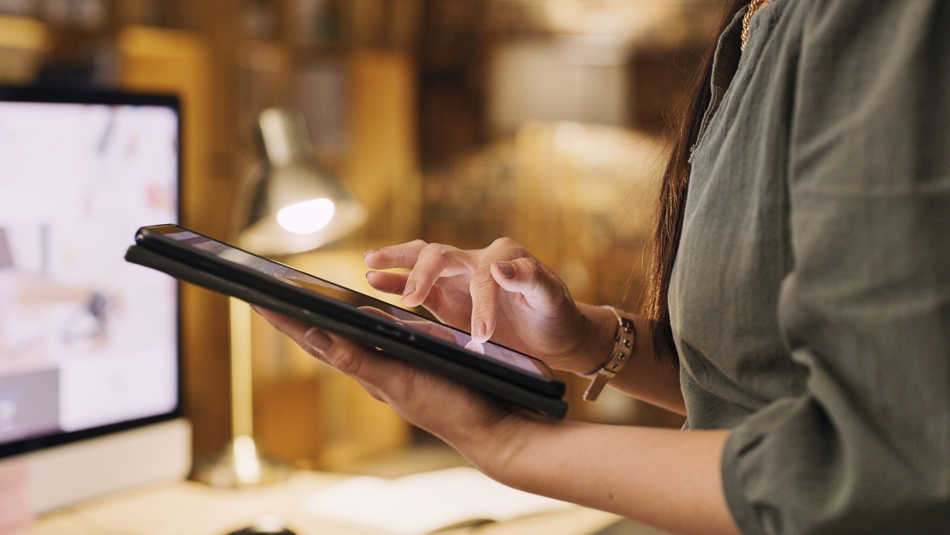 Hands of woman in office, scroll on tablet and overtime at design agency, reading email or social media. Night job, project manager or designer in digital marketing, planning and checking app online.